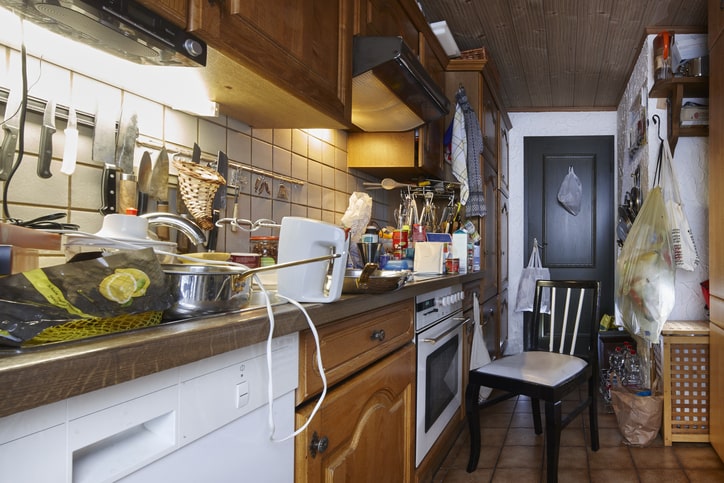 Cluttered kitchen counter not making optimal use of cabinet storage.
