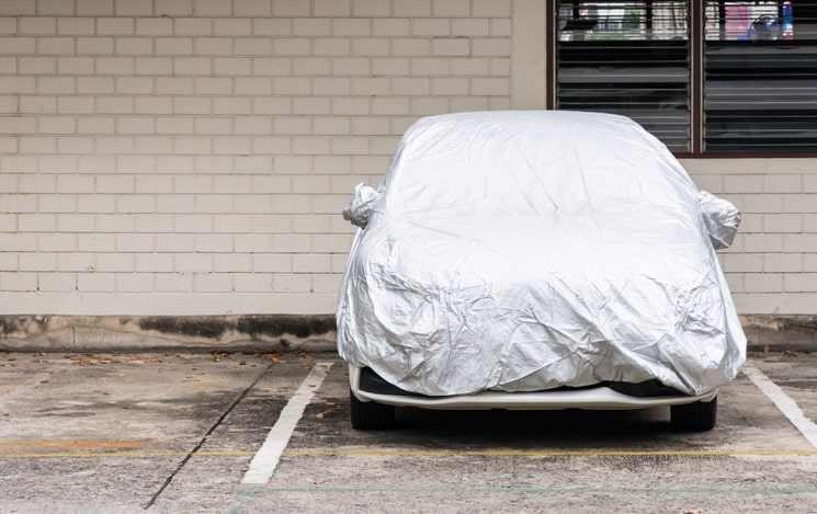 A car with a protective cover over the top in a parking lot